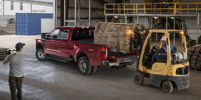 Red Super Duty unloading construction materials with forklift nearby